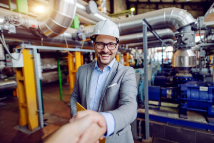 Accountmanager en klant bezegelen een deal met een handshake in de fabriek, symbool voor vertrouwen en commerciële samenwerking in B2B